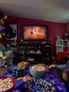 two people sitting in front of a television watching tv and eating popcorn at a party