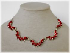 a necklace with red glass beads on a white mannequin