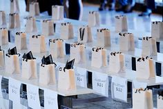 many small white bags are lined up on the table with black ribbons and tags attached to them