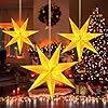 lighted christmas trees and star decorations in front of a window