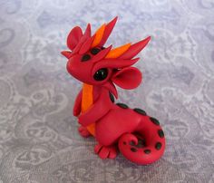 a red and black dragon figurine sitting on top of a gray tablecloth