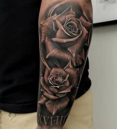 a man with a black and grey rose tattoo on his arm