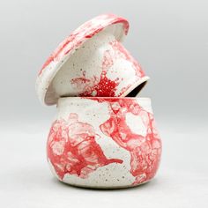 a red and white ceramic container sitting on top of a table