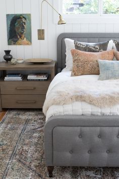 a bed with pillows and blankets on top of it next to a window in a bedroom