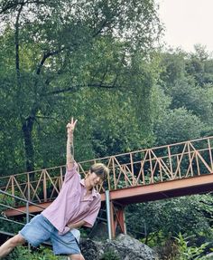 a person jumping up in the air with a frisbee near a bridge and trees