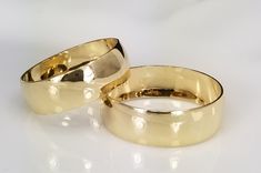 two gold wedding rings on a white background