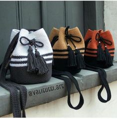 four crocheted purses are lined up on a ledge