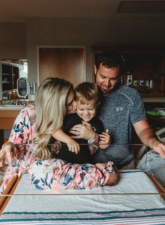 a man, woman and child sitting on top of a bed with their arms around each other