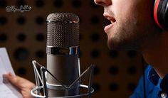 a man with headphones on is singing into a microphone and paper in front of him