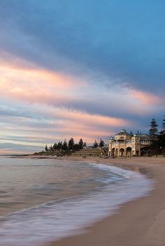 a beach with waves coming in to the shore and a building on top of it