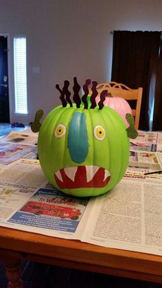 a green pumpkin decorated like a monster on top of a table