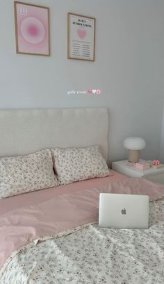 a laptop computer sitting on top of a bed next to pillows and blankets in a bedroom