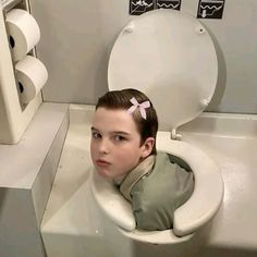 a young boy is sitting in a toilet