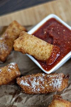 some fried food is in a white bowl and on a brown paper with dipping sauce