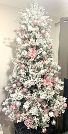 a white and pink christmas tree with ornaments