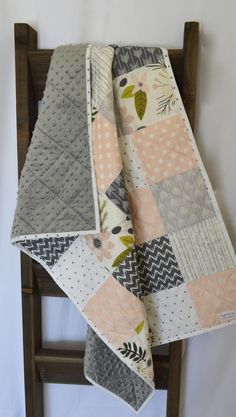 a quilted blanket sitting on top of a wooden chair next to a white wall