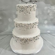 a three tiered wedding cake with white frosting and pearls