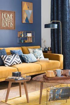 a living room with blue walls and yellow furniture in the center, along with coffee table