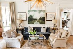 a living room with couches, chairs and a coffee table in front of a painting