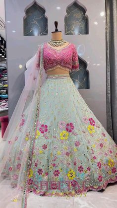 a dress on display in front of a window with flowers and pearls around the skirt