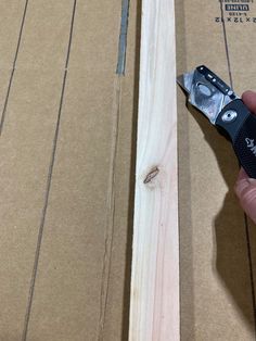 a person holding a pair of pliers in front of a piece of wood that has been cut