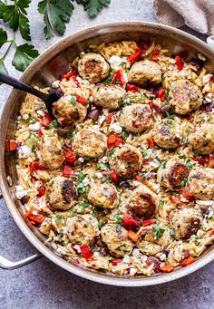 a skillet filled with meatballs and rice on top of a table next to parsley