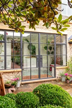 an outside view of a house with many windows and plants in the front garden area