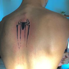 the back of a man's upper body with a spider - man tattoo on it