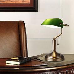 a desk lamp sitting on top of a wooden table next to a brown leather chair