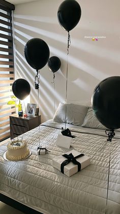 a bed with black balloons and a cake on it