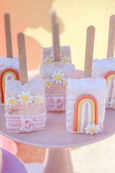 there are many small cakes with rainbows on the top and flowers on the bottom