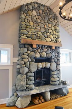 a stone fireplace in a living room with wood flooring