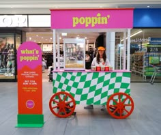 a woman standing behind a poppin's ice cream cart in a shopping mall