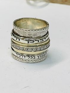 "9K Gold and sterling silver spinner ring with the Hebrew inscription reads: \" יברכך ה וישמרך (The Lord Bless You & Keep You) כי מלאכיו מצוה לך לשמרך בכל דרכיך ( the angels of god will protect you all your ways) Details: ♦ Returns accepted ♦ Materials: Sterling silver 925, 9k yellow gold ♦ Ring Width: 0.63 inches // 17mm ♦ All of my designs are handmade. ♦ Arrives in an elegant gift package. ♦ Not sure what size you need? Check this link: http://findmyringsize.com. You have the option to ch Silver Engraved Ring Stamped 14k For Promise, Silver Promise Ring Stamped 14k, Spiritual Silver Engraved Ring For Anniversary, Silver Stackable Rings Stamped 14k As Gift, Silver Spiritual Engraved Ring For Anniversary, Sterling Silver Rings With Rotating Bezel For Anniversary, Silver Sterling Engraved Ring For Marriage, Silver Stackable Wedding Rings Stamped 14k, Silver Sterling Silver Ring With Rotating Bezel