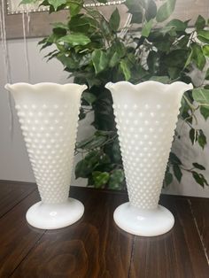 two white vases sitting on top of a wooden table