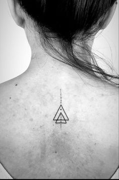 a woman's back neck with a small triangle tattoo on it