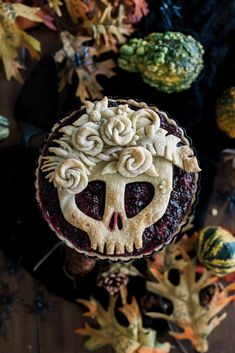 a close up of a pie on a table with autumn leaves and pumpkins in the background