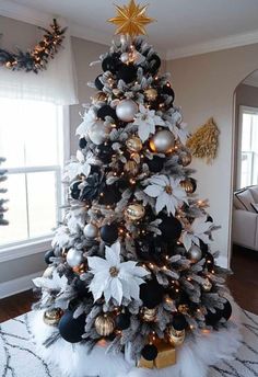 a christmas tree decorated with black, white and gold ornaments is in the middle of a living room