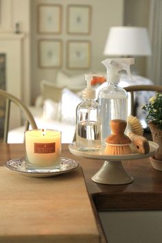 a candle on a table next to a glass bottle with a brush and soap dispenser