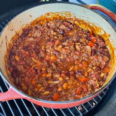 a pot filled with chili and beans on top of a grill