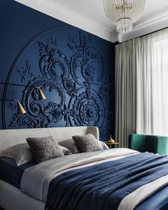 a large bed sitting under a blue wall next to a chandelier and window