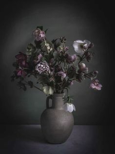 a vase filled with lots of flowers sitting on top of a table next to a wall