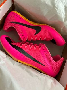 a pair of pink and black nike shoes in a box on top of white paper