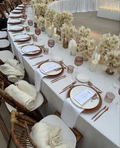 the table is set with white and gold plates, napkins, silverware, and flowers