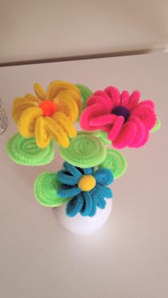 three colorful flowers sitting on top of a white table