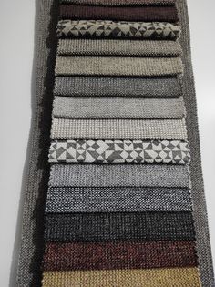 a pile of knitted rugs sitting on top of a white table next to each other