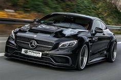 the front end of a black mercedes s - class coupe driving on a road