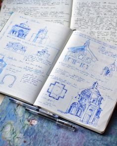 an open notebook with drawings on it and a pen in front of the pages that have been drawn