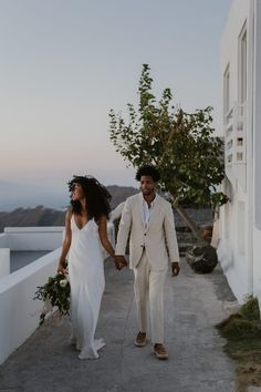 a man and woman walking down a path holding hands