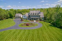 an aerial view of a large home in the middle of a lush green field with lots of trees